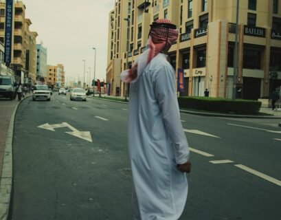 a man walking down a street in a white outfit