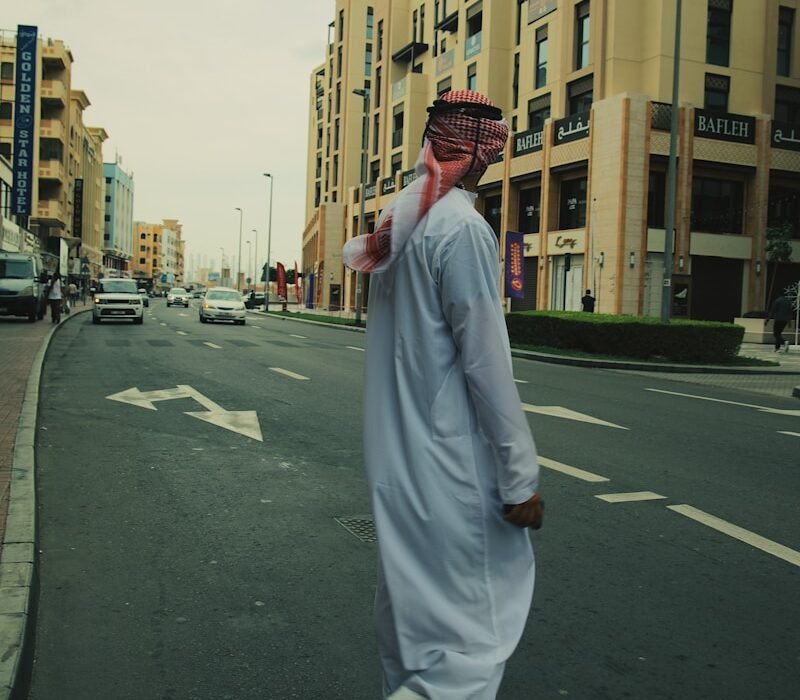 a man walking down a street in a white outfit